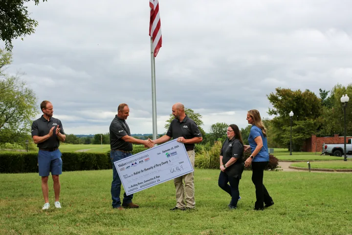 Participants arranging the Habitat for Humanity presentation check on the lawn.